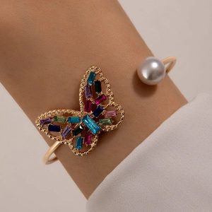 Gros plan d'un bracelet doré avec papillon en cristal coloré et perle élégante