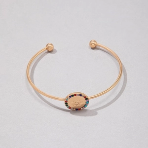 Détail macro du bracelet doré en C avec motif soleil et strass multicolores