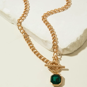 Détail du collier chaîne dorée avec pendentif émeraude et fermoir à bascule de type OT
