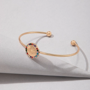 Détail macro du bracelet ouvert doré avec pendentif soleil et cristaux colorés