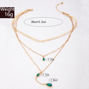 Vue détaillée du collier triple rang doré avec pendentifs gouttes vert émeraude
