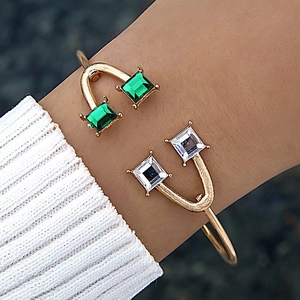 Détail d'un bracelet ouvert serti de pierres émeraude et zircon sur un anneau doré poli