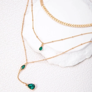 Détail de colliers dorés à trois rangs avec pendentifs en pierres vertes en goutte