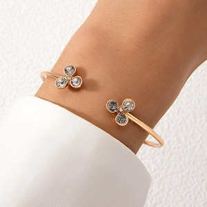 Gros plan d'un bracelet ouvert doré orné de fleurs en cristal porté au poignet