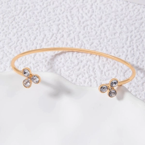 Détail d'un bracelet ouvert doré orné de fleurs délicates et de cristaux étincelants