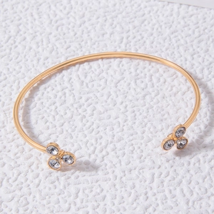 Détail d'un bracelet jonc doré orné de grappes de strass blancs brillants aux extrémités