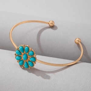 Détail d'un bracelet ouvert doré avec un motif floral de pierres turquoises vintage