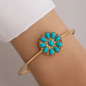Détail du bracelet fleur dorée bohème avec pétales en turquoise sur poignet féminin
