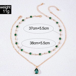Détail du collier doré double rang avec pendentif goutte émeraude et cristaux
