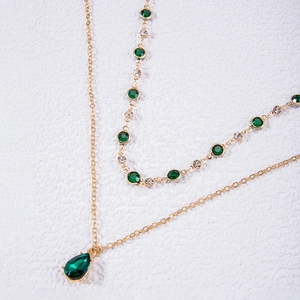 Vue détaillée du collier doré à double couche avec un pendentif vert en forme de poire