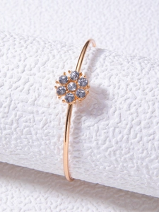 Détail d'un bracelet ouvert doré orné d'une fleur sertie de sept zircons étincelants