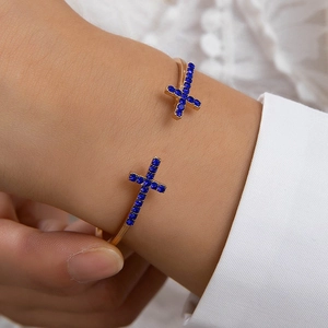 Vue détaillée d'un jonc ouvert doré avec des croix serties de pierres bleu marine