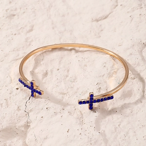Vue détaillée d'un bracelet jonc doré en forme de C avec des croix en cristal bleu