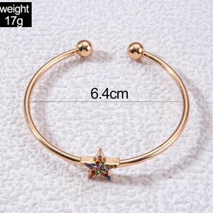 Détail d'un bracelet jonc étoile dorée avec strass colorés et diamètre de 6,4 cm