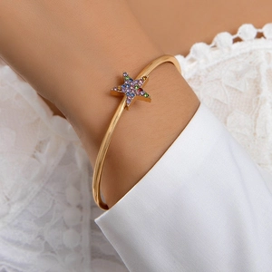 Gros plan détaillé d'un bracelet ouvert étoile dorée avec strass colorés sur dentelle