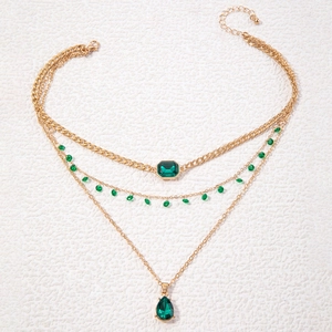 Gedetailleerde gelaagde gouden ketting met smaragdgroene stenen en druppelvormige hanger