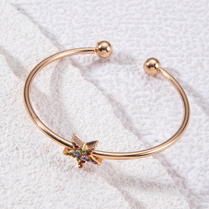 Détail d'un bracelet ouvert doré avec une étoile sertie de cristaux multicolores