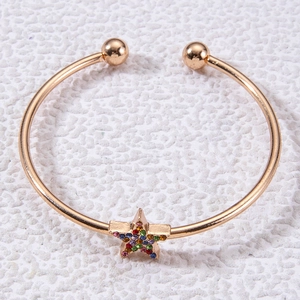 Détail d'un bracelet ouvert doré avec une étoile sertie de strass multicolores