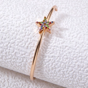 Détail d'un bracelet doré ouvert avec une étoile sertie de strass multicolores brillants