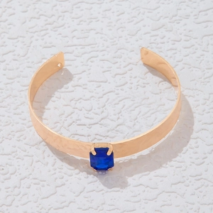 Détail d'un bracelet jonc doré ouvert orné d'une grande pierre bleue rectangulaire