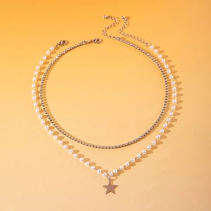 Detail van een gelaagde ketting met parels, strass en een zilveren sterhanger