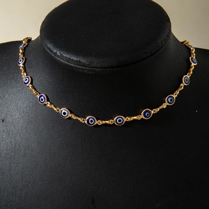 Detail van gouden evil eye ketting met blauwe kralen op een zwart displaymodel