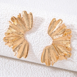 Macro view of gold flower petal earrings showing radial texture and wavy metallic edges