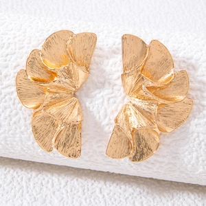 Macro shot of layered gold fan-shaped earrings with textured brushed metal finish