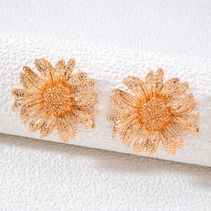Close-up of gold flower earrings with matte metal texture and layered petals detail