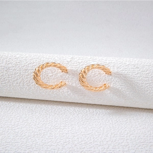 Close-up of golden C-shaped hoop earrings with twisted rope texture on a white display