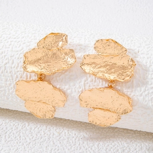 Detailed close-up of matte gold textured alloy earrings with irregular geometric layers
