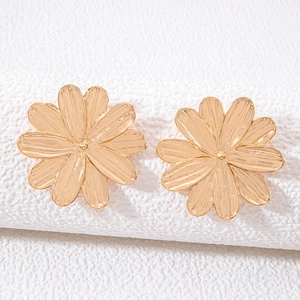 Macro detail of gold flower earrings showing layered petals and brushed metal texture