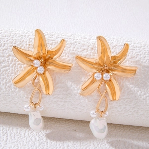 Detailed macro view of matte gold floral earrings with pearls and baroque drop