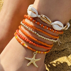 Detalle del set de tobilleras bohemias con cuentas naranjas, conchas y una estrella de mar