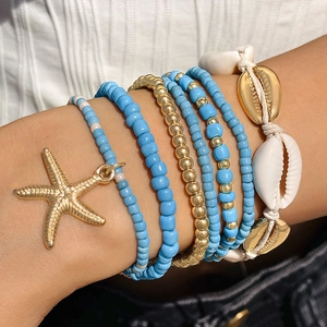 Detalle del conjunto de pulseras bohemias con colgantes de estrella de mar y conchas