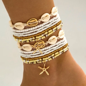 Detalle del conjunto de tobilleras bohemias con conchas blancas y colgante de estrella de mar