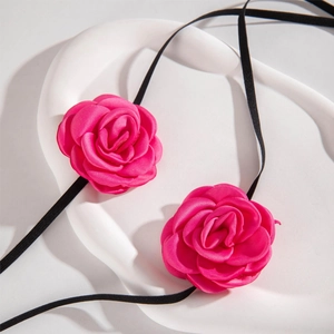 Detail of rose pink satin flower accessories with black elastic ribbon on white tray