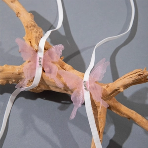Close-up of pink tulle butterfly hairband with sparkling rhinestones on wood branch