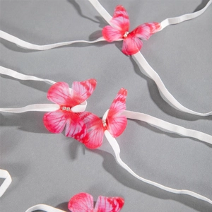 Close-up of pink fabric butterflies with rhinestones on white elastic leg chain straps