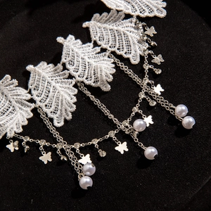 Detail of white lace choker featuring silver chains with butterfly pendants and pearls