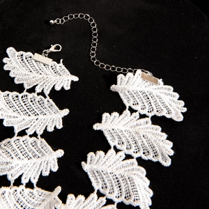 Detail of white lace choker with leaf embroidery and silver lobster clasp on velvet