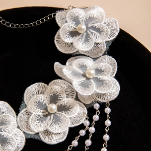 Macro detail of white lace flower necklace with pearls and elegant silver fringe chains