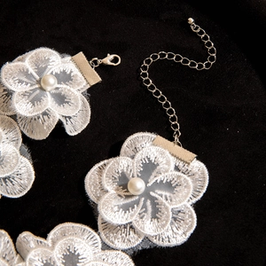 Macro view of white floral lace choker featuring pearl accents and adjustable silver chain