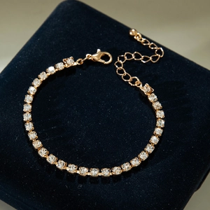 Close-up of adjustable golden tennis bracelet with square-cut crystals on black velvet