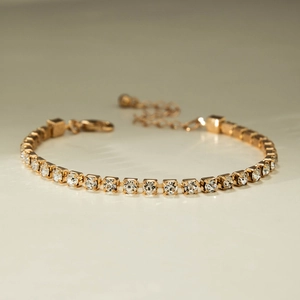 Detailed macro view of a classic gold-plated tennis bracelet with shimmering crystals