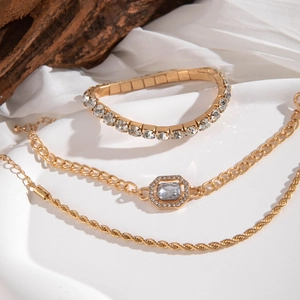 Three-piece gold chain bracelet set with crystals and twisted rope details on silk