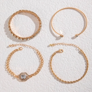 Detail of four-piece gold bracelet set with twisted chain and rhinestone accents