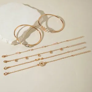 Close-up of 6-piece gold charm bracelet set with arrow cuff and gemstone details