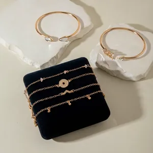 Macro detail of gold-plated twisted bangles and layered charms with faux gemstones