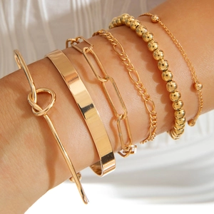 Close-up of 6pcs gold stackable bracelets with knot and link designs on female wrist